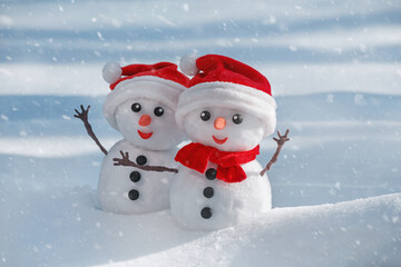 View of a couple of snowmen in a santa hats on their heads in a winter forest. Holiday christmas...