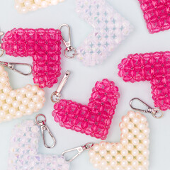 Different handcraft keychains in a heart shape made from acrylic beads scattered on a blue background.