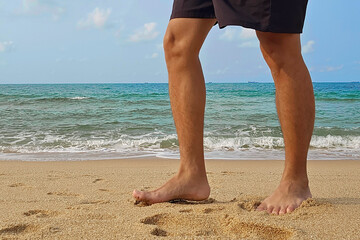 Barefoot of man walking on the beach; Healthy activity concept