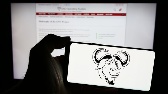 Stuttgart, Germany - 04-05-2024: Person holding mobile phone with logo of software collaboration project GNU Project in front of web page. Focus on phone display.