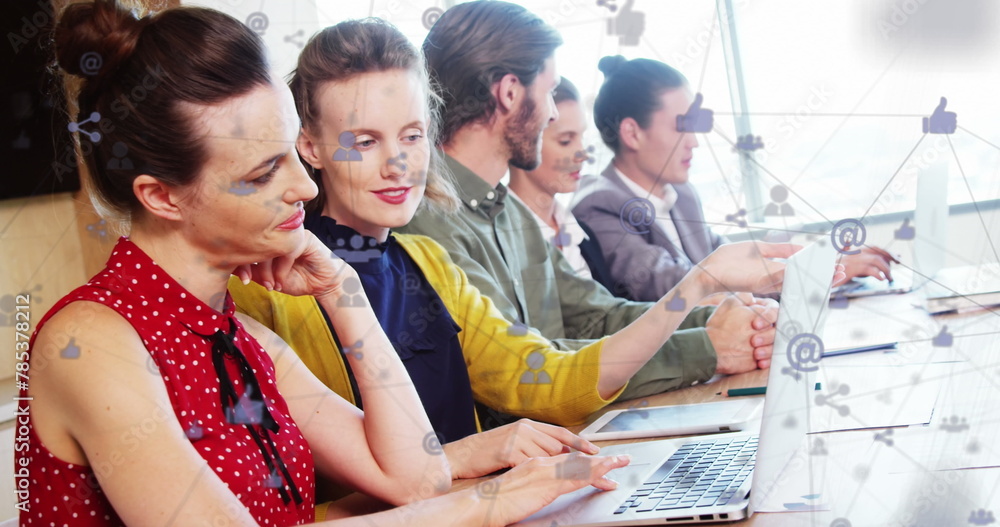 Poster image of computer icons connected with lines over diverse coworkers using technology on desk