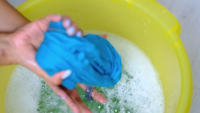 Woman Wrings Out T-shirt Washed Clothes Squeezing Out Liquid by using Hands close-up