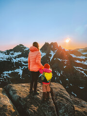 Family climbing mountains mother and child traveling in Norway summer vacations outdoor hiking adventure active healthy lifestyle, parent and kid on the top together enjoying midnight sun view