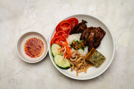 Cơm Tấm. Vietnamese Broken rice with grilled pork, steamed egg, and fresh vegetable