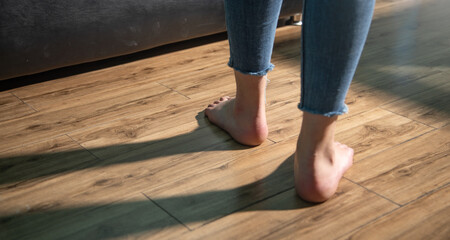 Barefoot woman walking on floor at home.