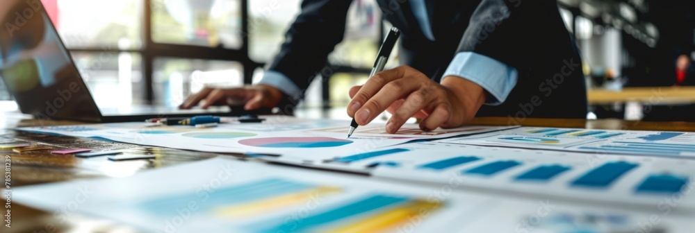 Poster business analysis with charts and laptop on desk - close-up of professional working with colorful fi
