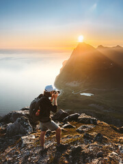 Man photographer with backpack and camera taking photo of sunset mountains in Norway, travel blogger lifestyle hobby concept adventure active vacations outdoor - 785382647