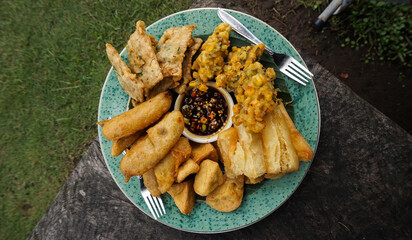 various fried foods served on plates that are famous in Indonesia, such as corn bakwan, mendoan,...