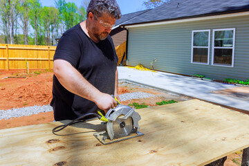 Carpenter trimming plywood board with handsaw