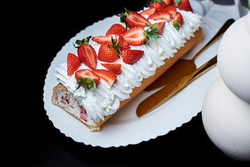 sponge roll with cream, decorated with fresh strawberries