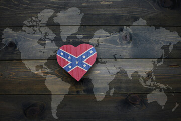 wooden heart with confederate flag near world map on the wooden background.