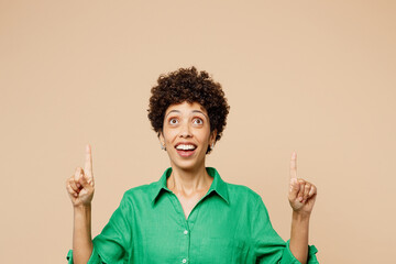 Young happy woman of African American ethnicity wear green shirt casual clothes point index finger...