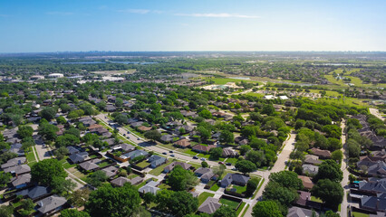 Suburbs subdivision with downtown Dallas background, row of residential houses with school district, natural lake, lush greenery landscape, upscale homes swimming pool, grassy front yard, aerial