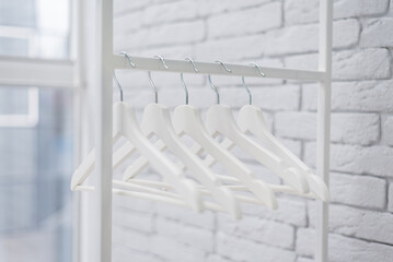 Many wooden white hangers on a rod, isolated on white wall background. Store concept, sale, design,...