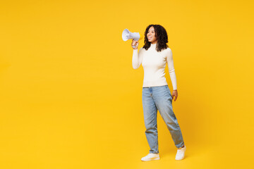 Full body little kid teen girl of African American ethnicity wear white casual clothes hold megaphone scream announces discounts sale Hurry up isolated on plain yellow background. Childhood concept. - obrazy, fototapety, plakaty