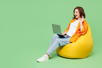 Full body young ginger IT woman wear orange shirt white t-shirt casual clothes sit in bag chair...