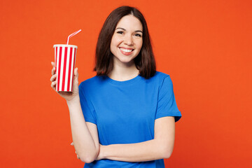 Young smiling fun happy woman she wear blue t-shirt casual clothes hold in hand cup of soda pop...