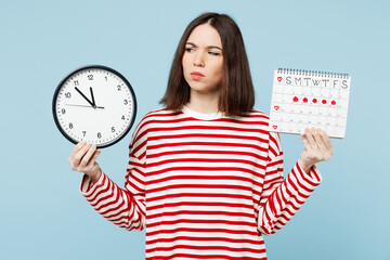 Young confused puzzled minded sad woman wears red casual clothes show clock hold female periods pms...