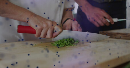 Image of dots forming dna helix over cropped hands of chef cutting vegetable over cutting board