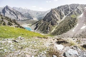 Fototapeta na wymiar Blue lake Kulikalon in the valley basin from the height of the pass on a sunny summer day in the Fan Mountains in Tajikistan