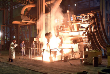 Workers in protective equipment in a foundry during the production of steel components - workplace industrial factory