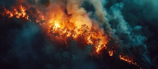 Foto op Canvas An aerial perspective capturing a forest fire with raging flames spreading across the landscape. © FryArt Studio