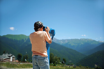 boy observing mountains panorama through stationary binoculars