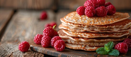 A neat stack of pancakes with vibrant fresh raspberries on top, creating a visually appealing...