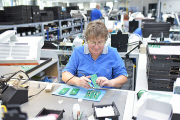 friendly woman working in a microelectronics manufacturing factory - component assembly and soldering
