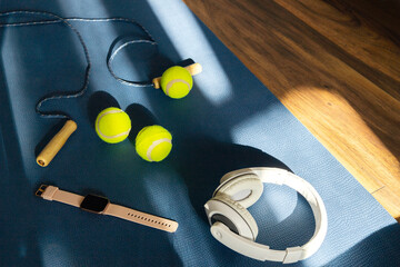 Sport accessories on blue yoga mat, on wooden floor. Natural light