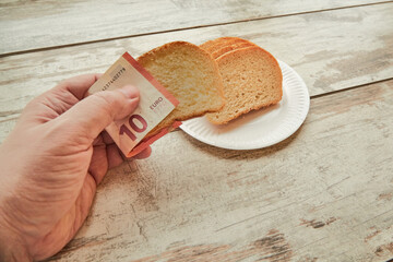 A hand takes bread using euro banknotes instead of a napkin, bread price increase, money and diet,...