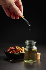 Dropping essential oil or herbal tincture into a small bottle.