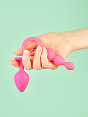 Woman's hand holding adult sex toy over mint background - 785414603