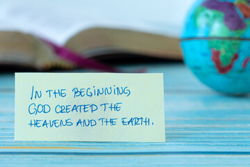 In the beginning God created heavens and earth, handwritten quote with world globe and open holy...