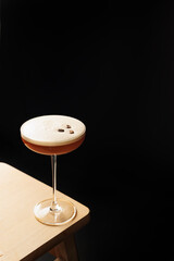 glass with alcoholic coffee cocktail decorated with roasted coffee beans on a black background....