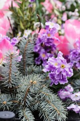 A colorful decoration with artificial flowers and natural fir branches.