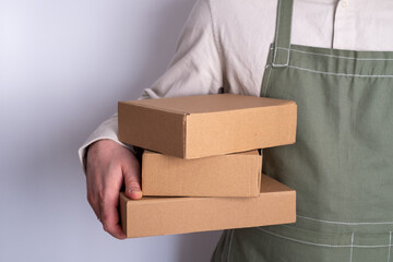 Man holds a paper box in his hand. Person with new package. Postal services, delivery. Kraft paper. Gift box, gift. Box close-up. Empty packaging, empty space. Communication of people. Cardboard case
