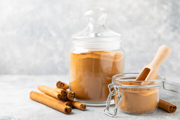 Cinnamon powder in a bowl on a textured wooden background. Spicy spice for baking, desserts and...
