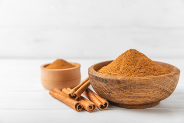 Cinnamon powder in a bowl on a textured wooden background. Spicy spice for baking, desserts and drinks. Fragrant ground cinnamon. Cinnamon stick. Place for text. Copy space.