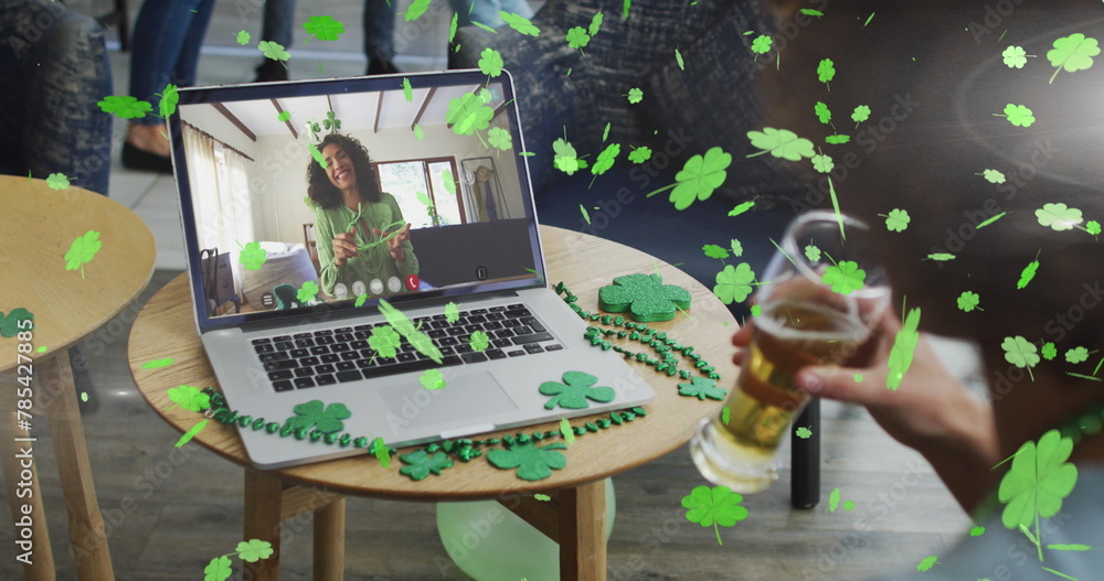 Poster Clover leaves falling against woman drinking beer while having a image call on laptop at a bar