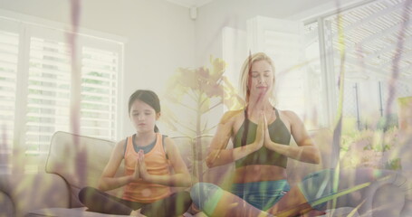 Image of grass moving over happy caucasian woman with her daughter doing yoga