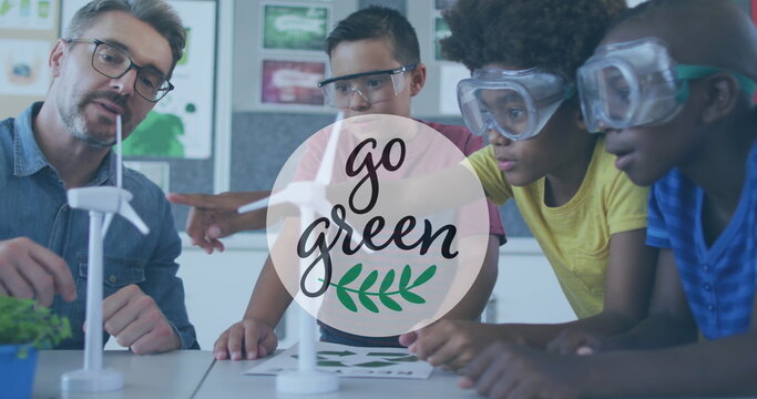 Image of go green text over male teacher and schoolboys looking at wind turbine models - Powered by Adobe