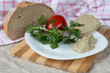 Aubergine cream on a white plate with bread and tomatoes.