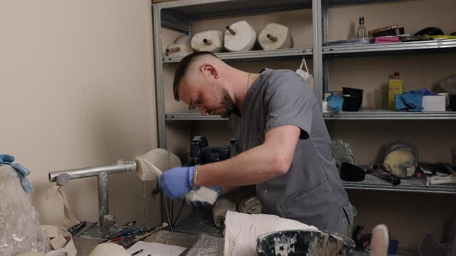 Plaster molds, Mold development, Crafting techniques. In professional studio, man meticulously crafting plaster mold for prosthetic leg intended for hip disarticulation.