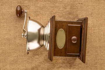 One manual, wooden coffee grinder on a jute cloth, macro, top view.