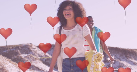 Image of hearts over happy african american couple at beach