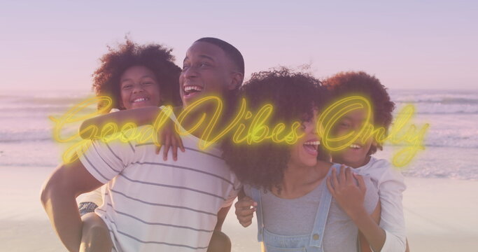 Image of good vibes only over happy african american family having fun on beach