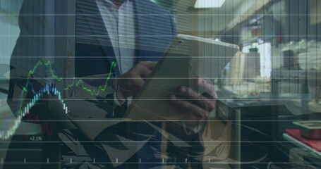 Image of financial data and graphs over hands of caucasian businessman using tablet