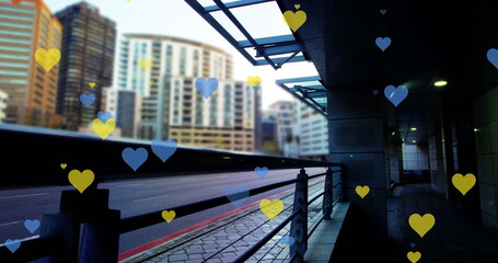 Image of yellow and blue hearts floating over cityscape