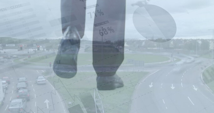 Image of statistical data processing over low section of businessman walking against cityscape